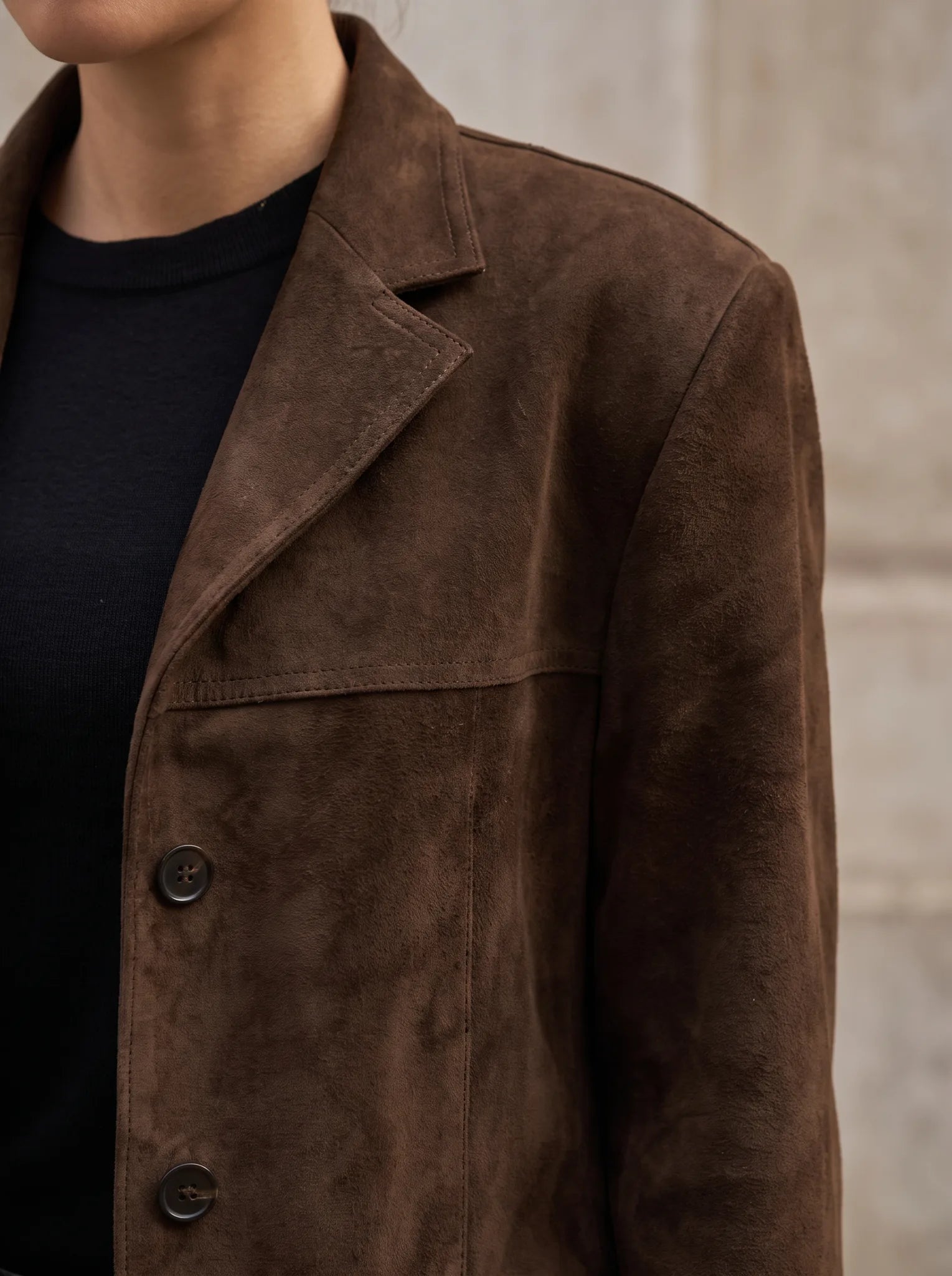 Close-up van de revers, knopen en suèdelook-structuur van de Florence blazer in donkerbruin
