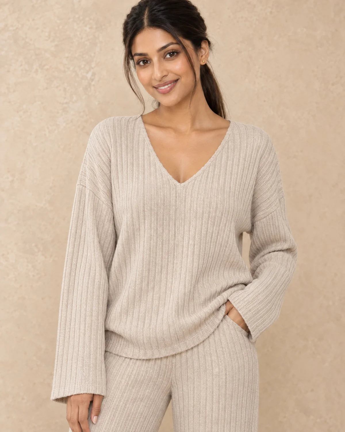 Gebreide Co-ord Set Dames met V-hals en Wijde Broek in Beige, gedragen door model, detail van V-hals en ribgebreide stof