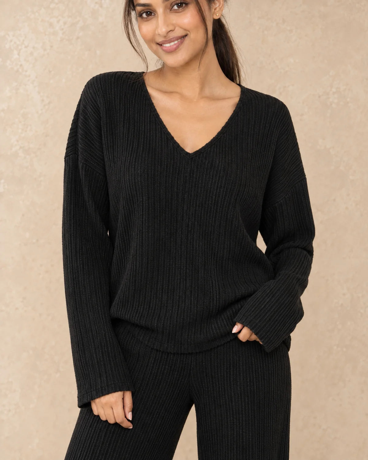 Gebreide Co-ord Set Dames met V-hals en Wijde Broek in Zwart, gedragen door model, detail van V-hals en ribgebreide stof