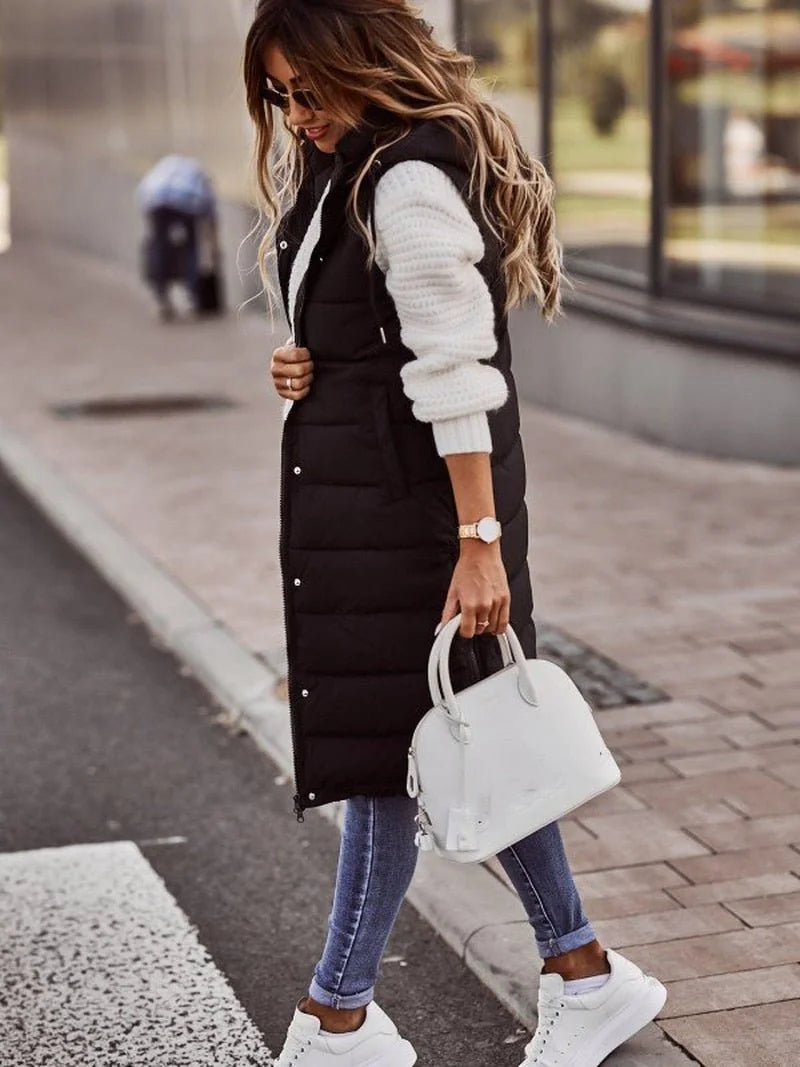 Lange Gewatteerde Bodywarmer Dames met Capuchon in Zwart, gedragen door model, vooraanzicht
